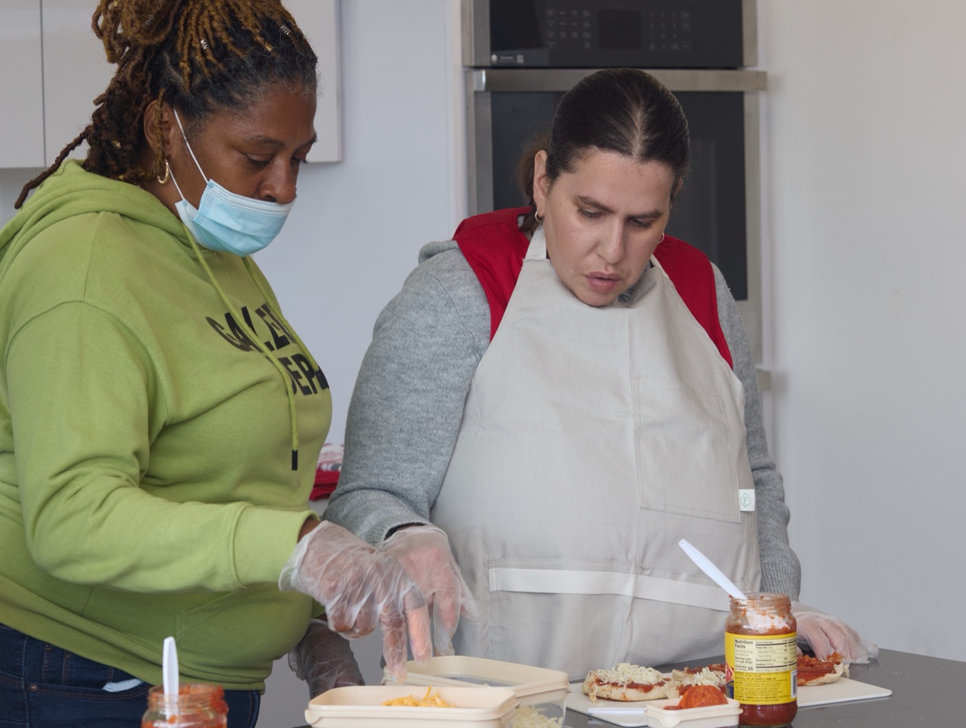 A staff member and a program participant preparing food together in the kitchen